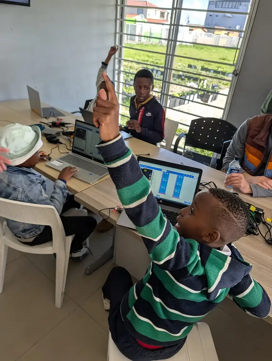 A learner raising his hand during a coding lesson at Nguzo Saba